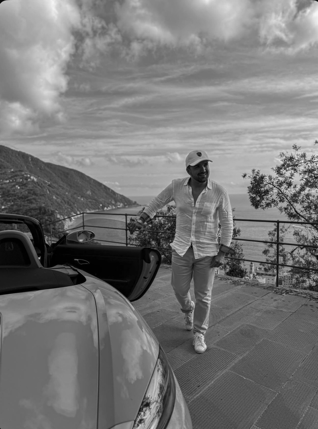 Simone Guiducci accanto alla sua Porsche cabrio su una terrazza affacciata sul mare della Riviera ligure a Portofino